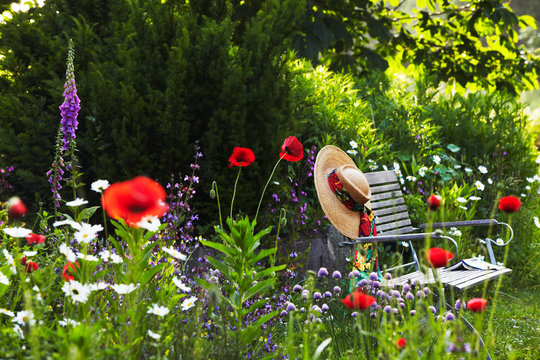 garden bench with straw hat within summer flowers 02