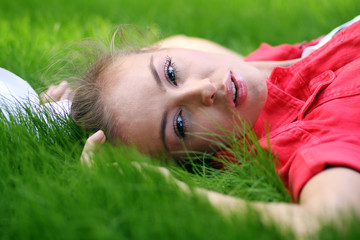 Cute young female lying on grass field at the park