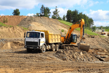 Fototapeta premium Backhoe loader loading dumper