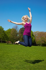 Blonde Frau springt im Park