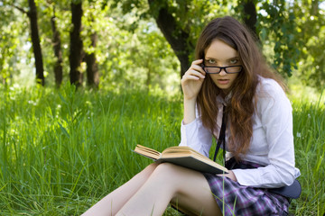 young schoolgirl in park read book