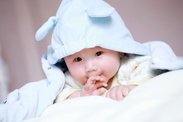 Cute little baby in bed, wearing a blue cartoon clothes
