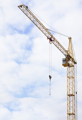Hoisting crane on a construction site in the cloudy sky