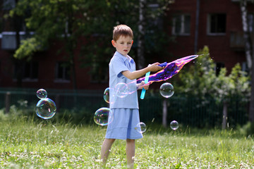 little boy is played with soap bubbles in the street