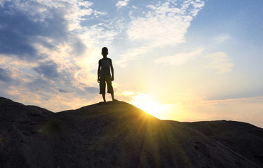 young man in sand desert in sundown silhouette