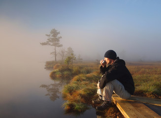 Hiker enjoying a morning coffee in a marsh - obrazy, fototapety, plakaty