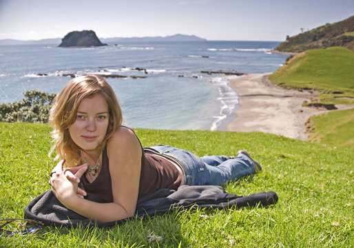 Blonde woman sitting on grass in New Zealand.