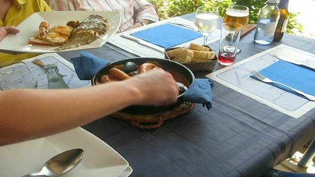 SIRVIENDO UN PLATO DE SUQUET DE PESCADO Y MARISCO