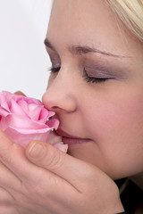 junge Frau riecht sinnlich an einer Rose