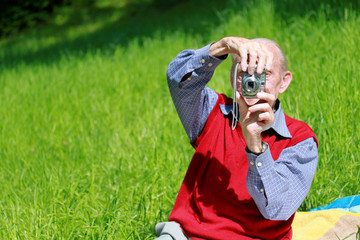 Alter Mann beim Fotografieren auf grüner Wiese