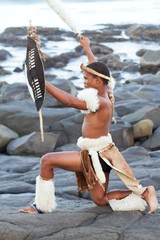 zulu man with traditonal shield on beach