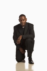 A Man Wearing A Clerical Collar Kneeling In Prayer