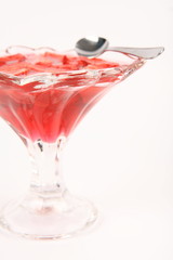 Jelly with strawberries in a glass cup with a spoon