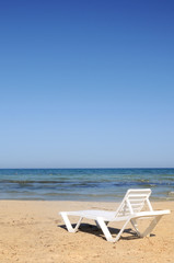 Fototapeta na wymiar deckchairs on the beach under blue sky