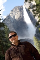 A young man smile in front of the Yosemite Falls.