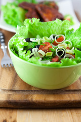 Salad with croutons and chicken wings in background