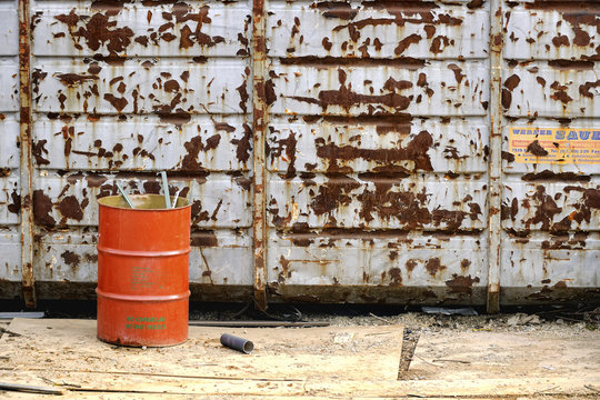 Orange Barrel Next To Weathered Dumpster