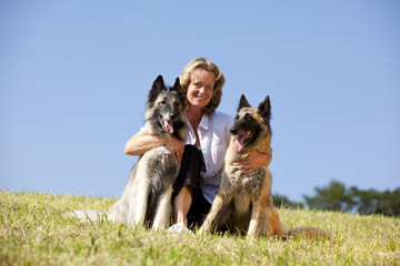hübsche blonde Frau mit zwei belgischen Schäferhunden