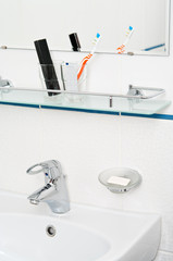 Bathroom accessories: tooth paste and brush on glass shelf