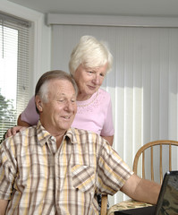 Senior couple brows Internet on their laptop.