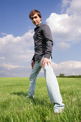 Fototapeta premium young man in black shirt standing on green lawn at summer time