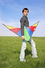 young man in black shirt holding multicolored kite at summer tim