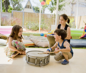 three kids having fun with drums