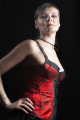 Sexy young woman in red corset against dark background