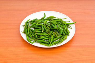 Hot peppers in the plate on wooden table