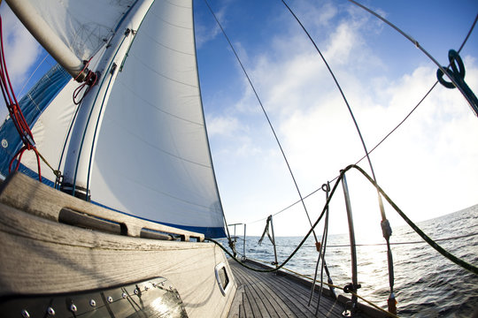 Sun behind white sails