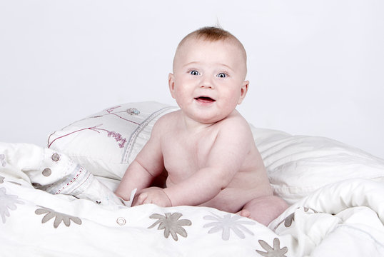 Very Cute Baby Boy on Duvet against Grey Background