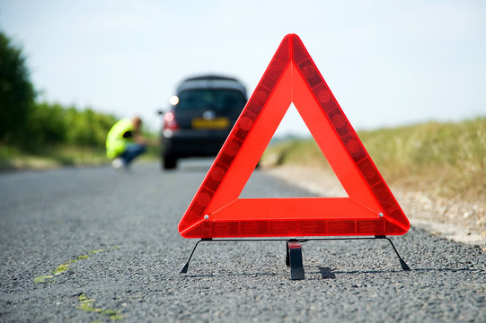 Red warning triangle with a broken down car