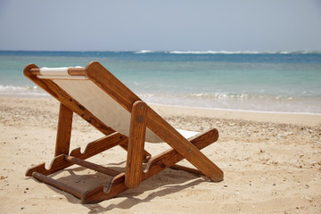 wooden chaise loundge on beach. sea and sky