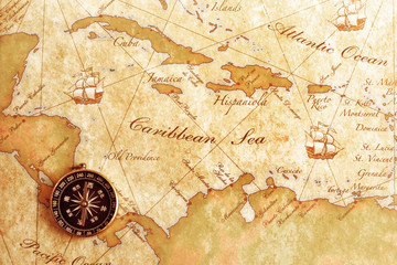 An old brass compass on a Treasure map background