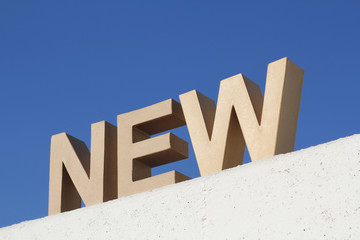 NEW Schriftzug auf weißer Betonmauer vor blauem Himmel