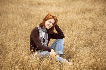 Naklejka na ściany i meble Beautiful red-haired girl at yellow autumn grass.