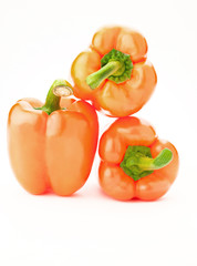 three orange peppers over white