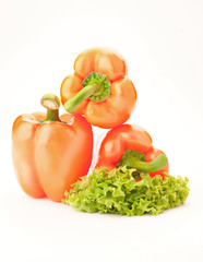 three orange sweet  peppers and salad over white