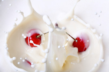A cherry falling into milk creating a splash