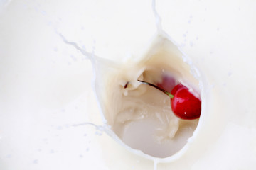 A cherry falling into milk creating a splash
