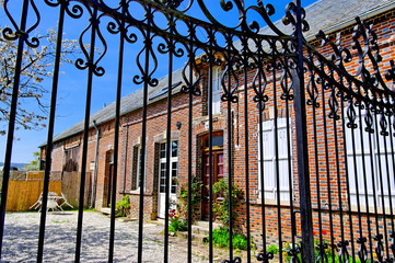 Maison de briques à travers le portail de fer.