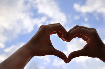 Hands shaped love on the blue sky