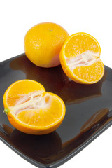 oranges on black plate isolated on white background