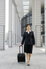 beautiful business woman walking down at station with a trunk