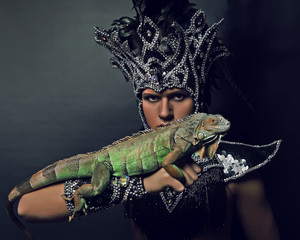 Young pagan priest in ritual suit with green iguana in his hands