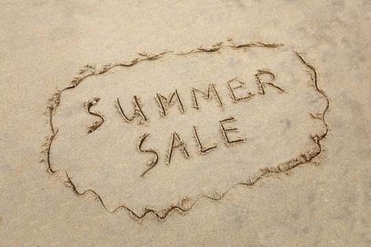 "Summer Sale" written in the sand at the beach.  Sales concept