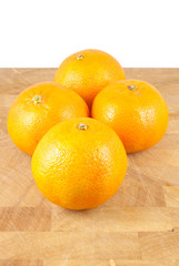 four small oranges on chopping block isolated on white
