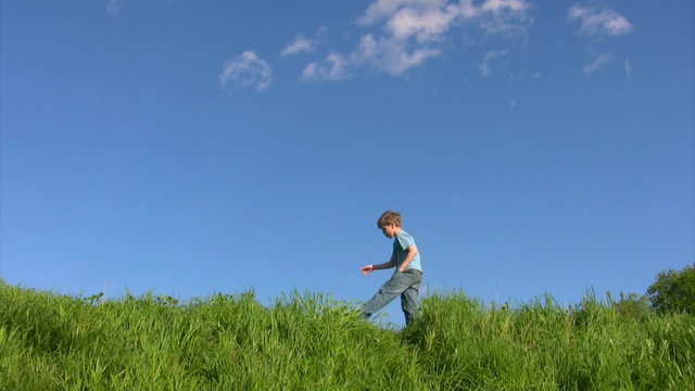 boy walking on grass in field under sky
