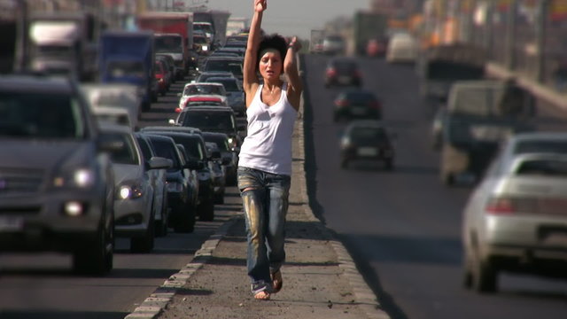 dancing girl walks on highway middle in city