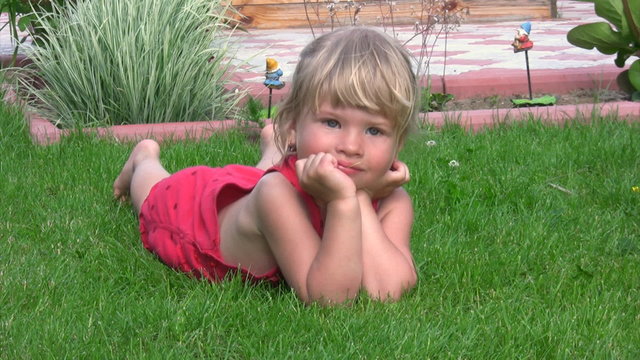 little girl lying on green grass in outlet